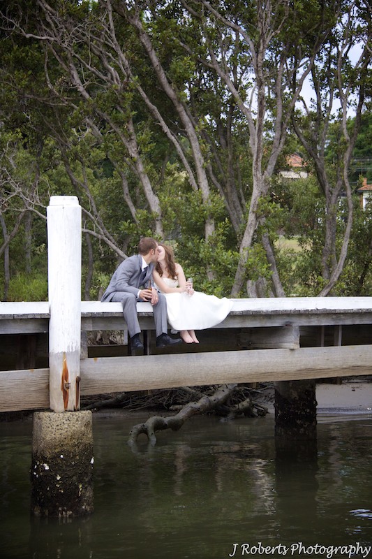Bride and groom kissing on a jetty - wedding photography sydney